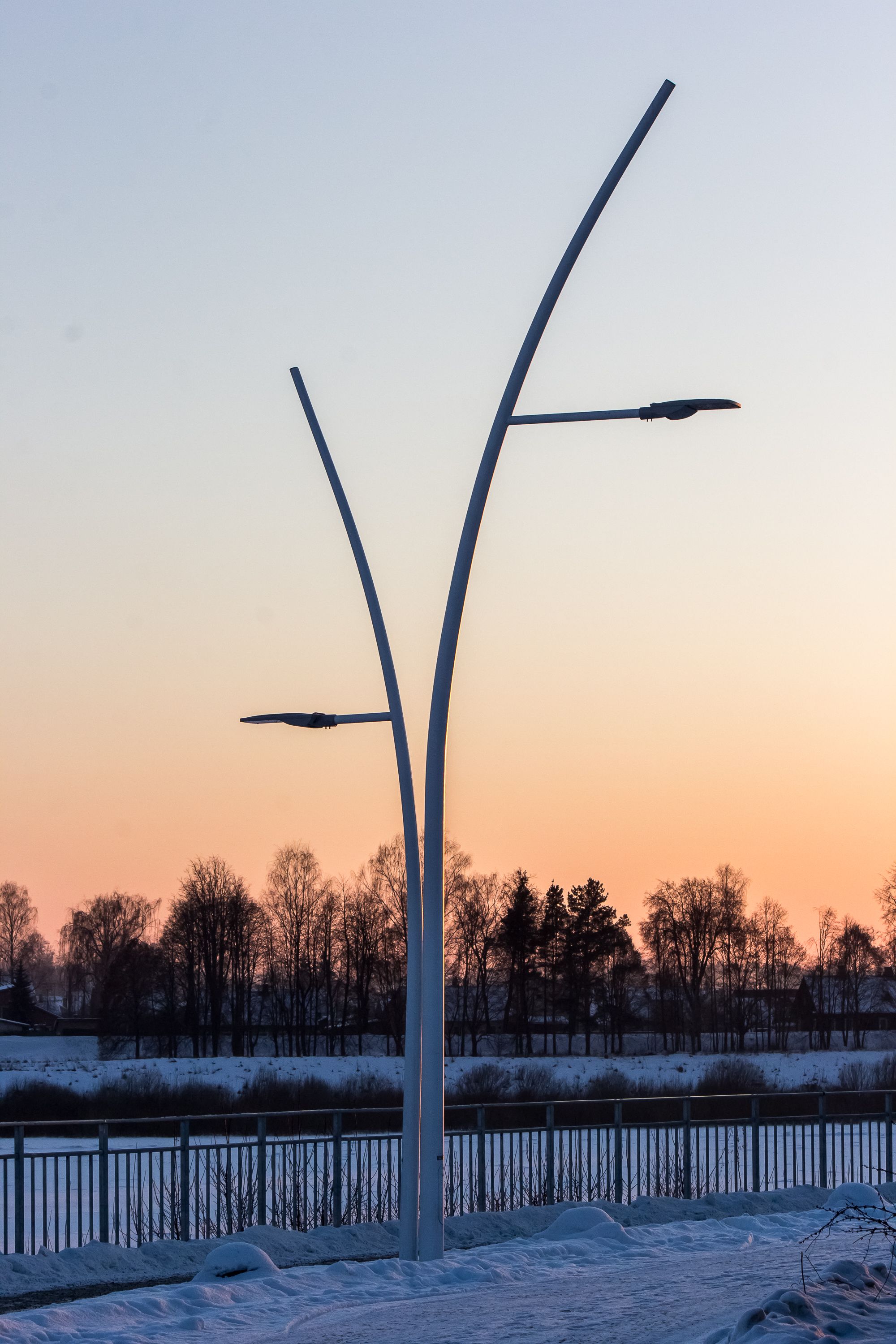 Gratis Elegante gadelamper mod en vintersolnedgang med snedækket jord. Lagerfoto
