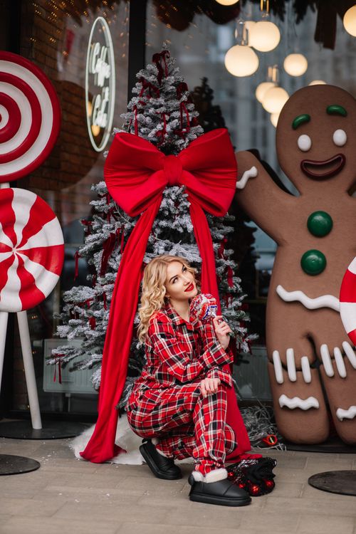 Free Woman in plaid pajamas beside Christmas tree and decorations. Stock Photo