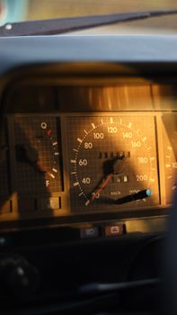 Close-up of a vintage car's speedometer with warm sunlight.