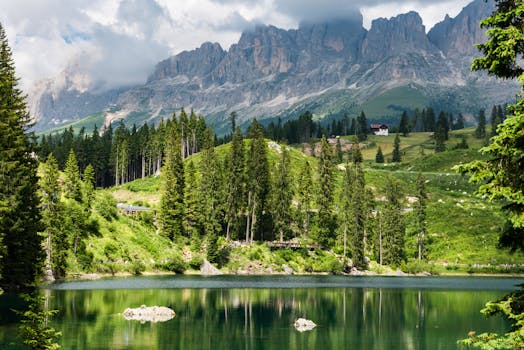 A tranquil view of Lake Carezza with reflecting waters and Dolomite mountains in Trentino, Italy.