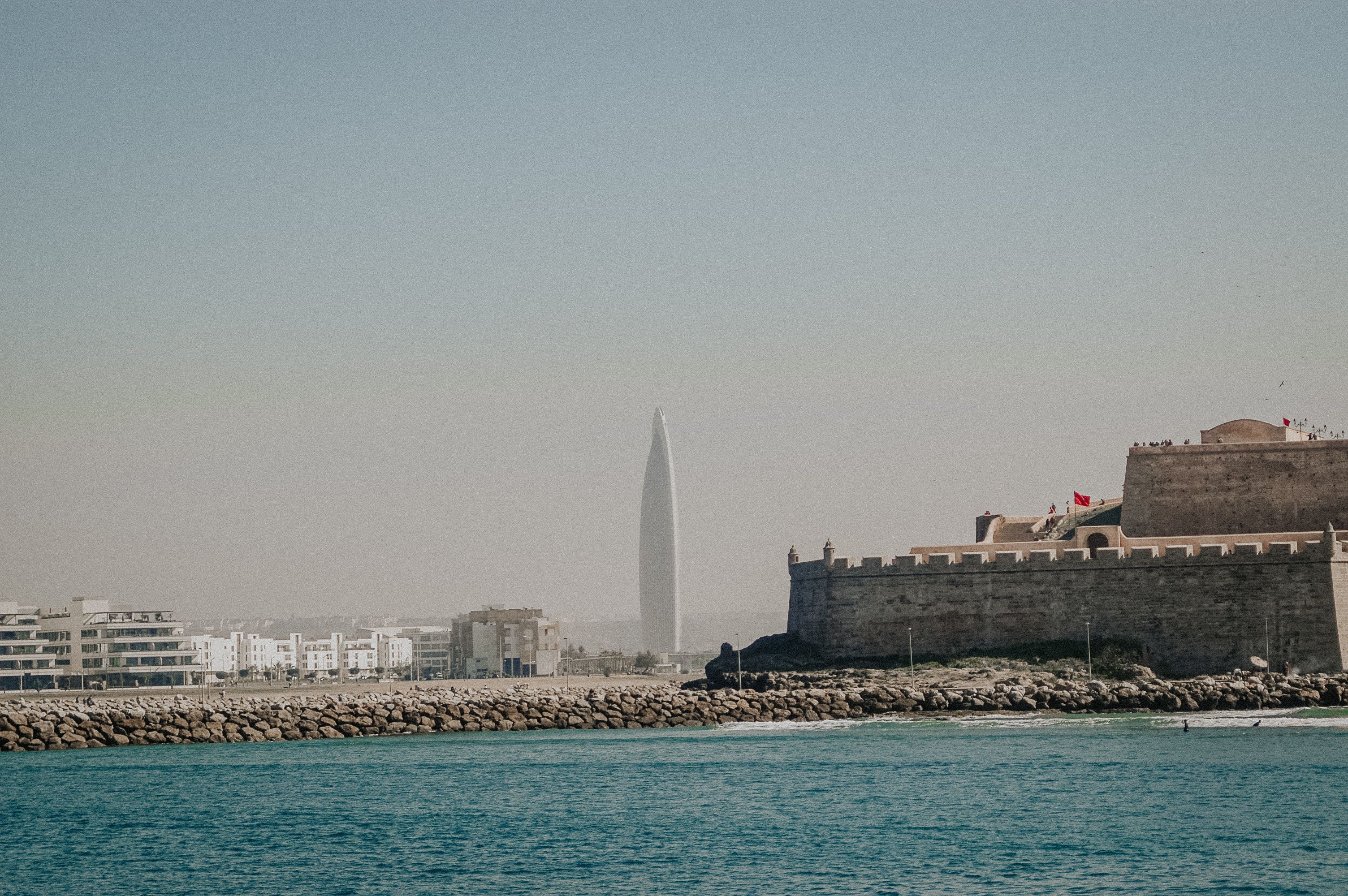 Modern Skyscraper and Historic Fort by Ocean · Free Stock Photo