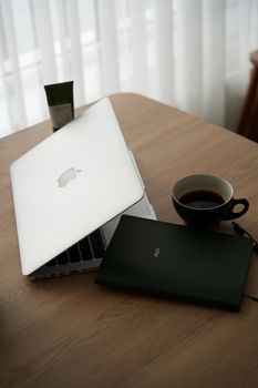 Sleek office desk featuring a laptop, coffee cup, and notebook. Ideal for productivity themes.
