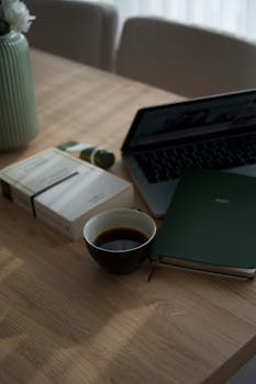 A minimalistic workspace with a cup of coffee, laptop, and books.