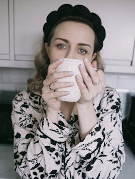 Woman enjoying a warm morning drink in pajamas, creating a cozy and comforting atmosphere.