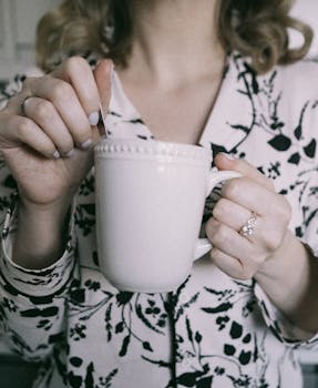 Person stirring coffee in a white mug during a relaxed morning at home.