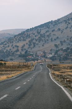 Serene mountain road with distant village, capturing a peaceful journey.