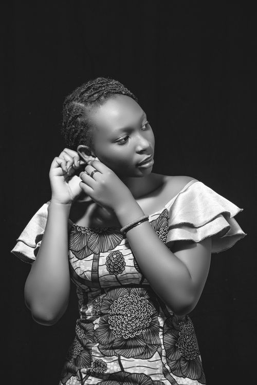 Free Black and white portrait of a woman adjusting earrings, showcasing elegance. Stock Photo