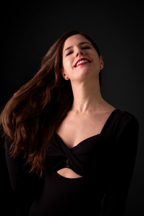 Free A charismatic woman with flowing hair and a radiant smile, captured against a dark background. Stock Photo