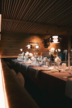 An elegant table set for a special occasion in a dimly lit restaurant, featuring white floral arrangements.