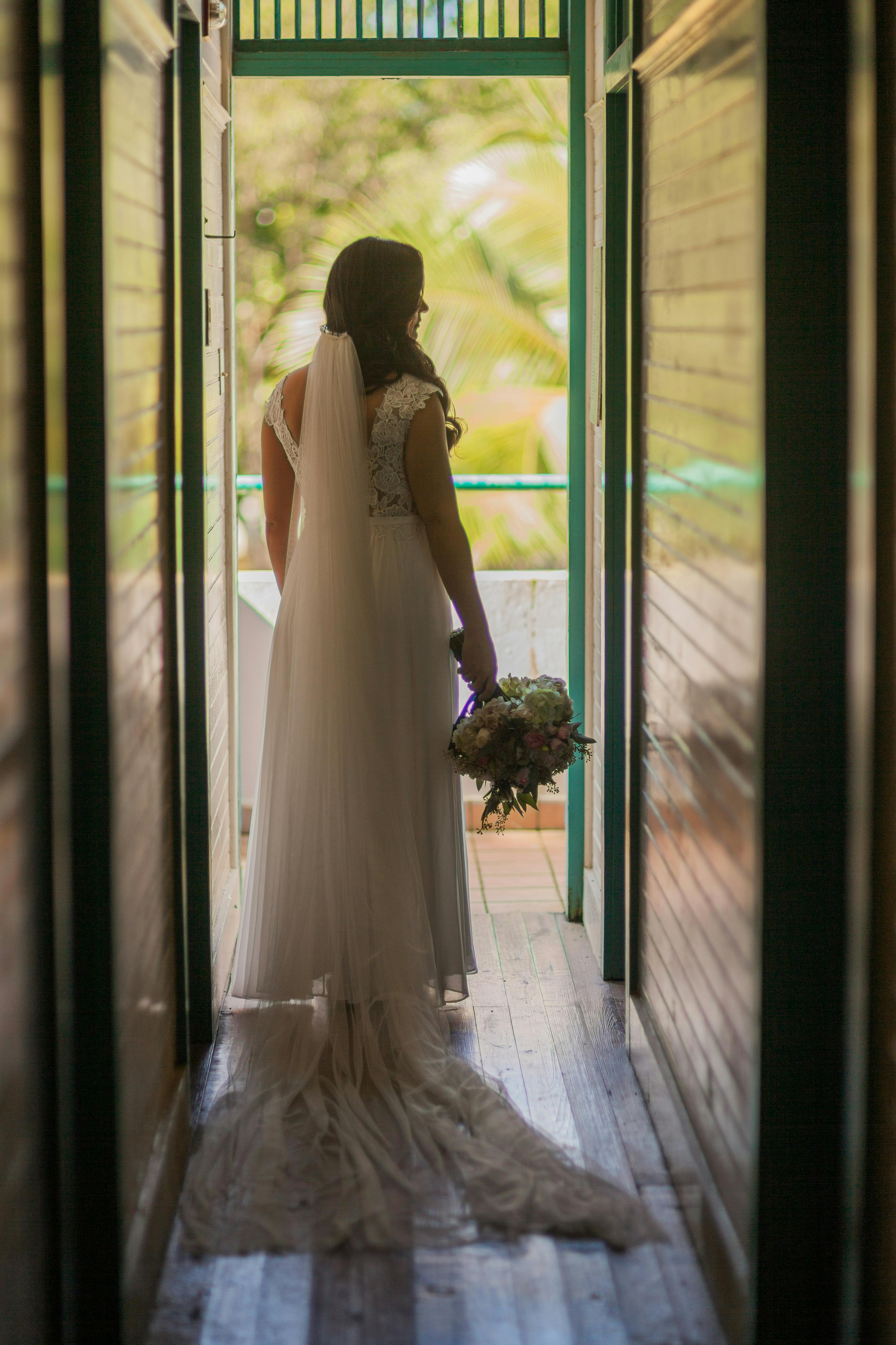 大厅里，一位身穿白色礼服的新娘手捧花束，对着镜头