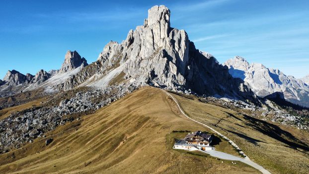 Stunning drone view of the majestic Dolomites in Veneto, Italy. Captures rugged peaks against a clear blue sky.