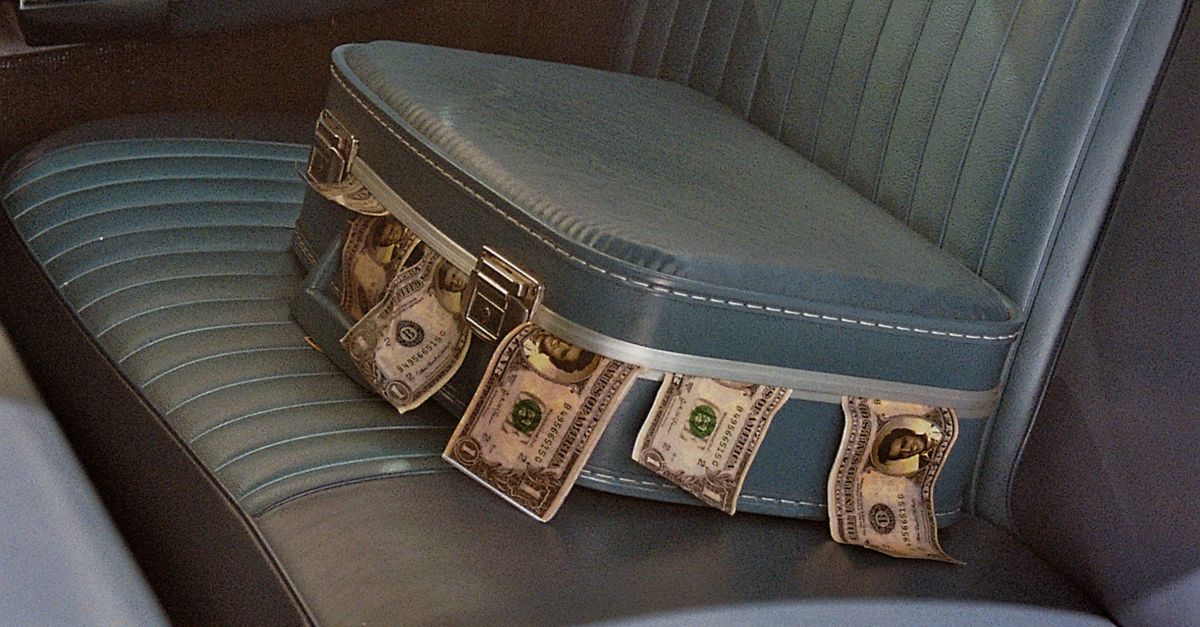 Rüyada Gizli Para Dolu Kasa Bulmak - Rüya Tabiri ve Anlamı - Inside view of a vintage car with a suitcase overflowing with cash on the back seat.