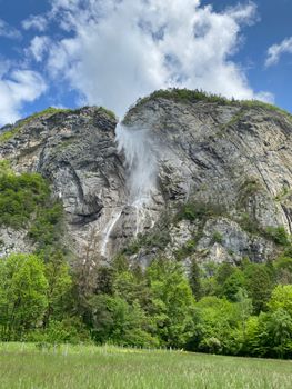 Breathtaking view of a cascading waterfall amid lush greenery in the Swiss Alps.