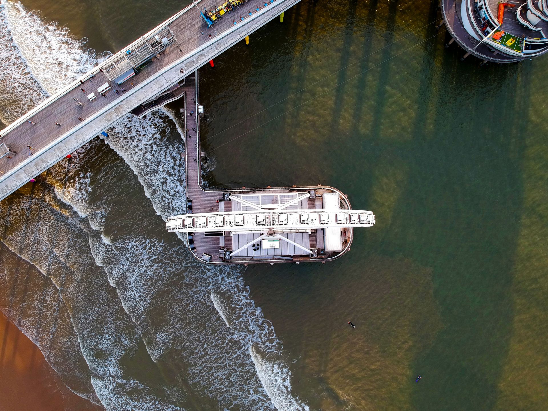 A drone shot capturing the pier and Ferris wheel at The Hague against the North Sea waves.