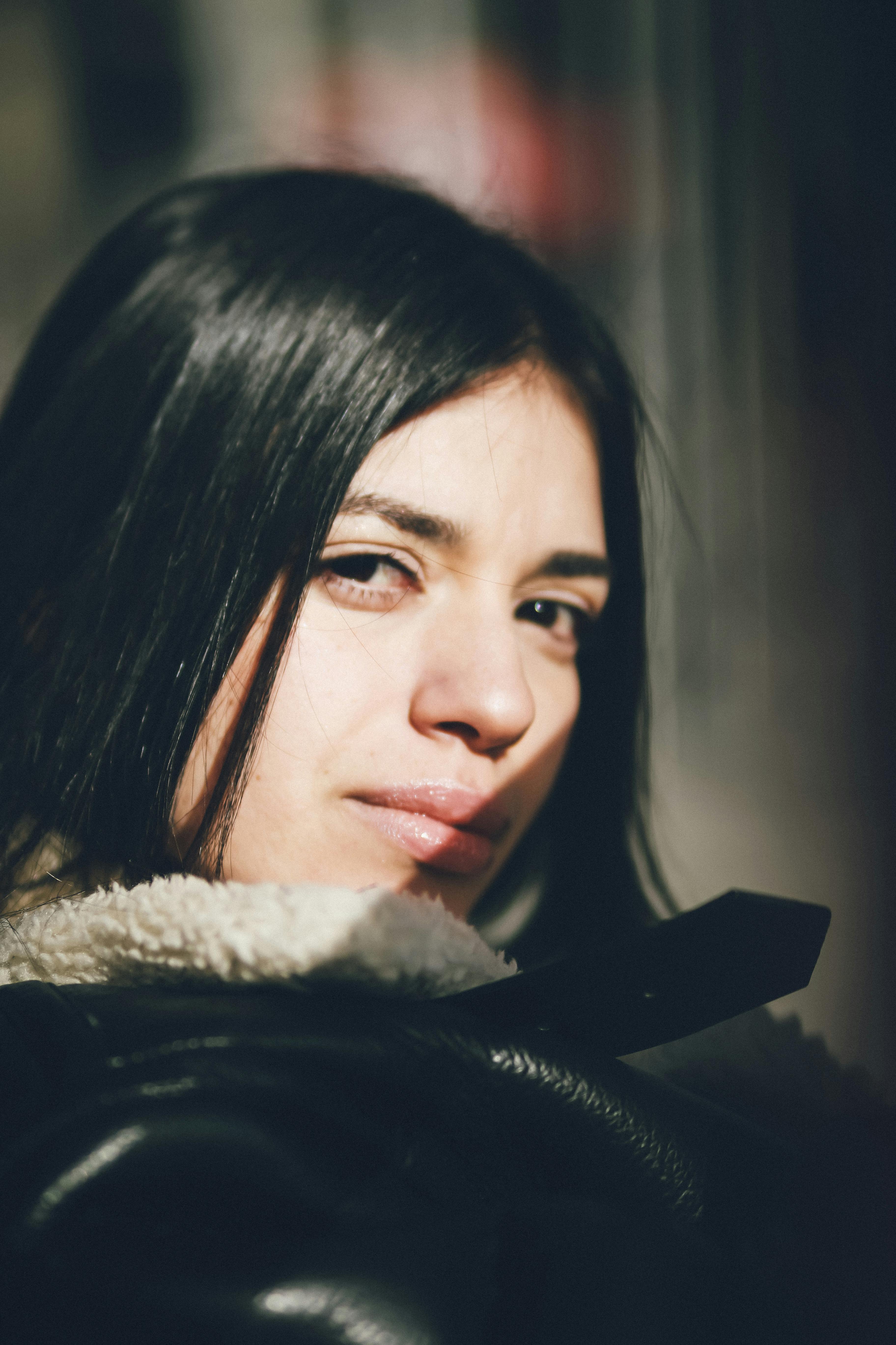 Kostenlos Nahaufnahme eines Frauenporträts im Sonnenlicht, das Kontemplation und Wärme hervorruft. Stock-Foto