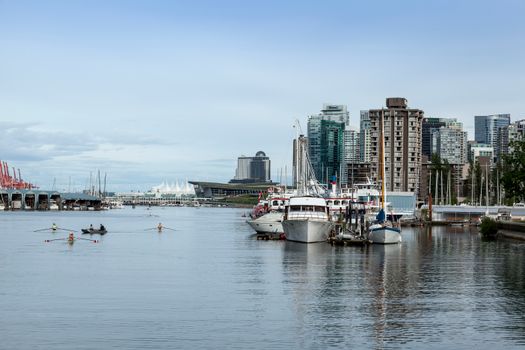 Scenic view of Vancouver harbor with boats and city skyline under a clear sky.