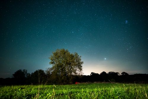 Free A stunning night sky full of stars above a serene countryside landscape in France. Stock Photo