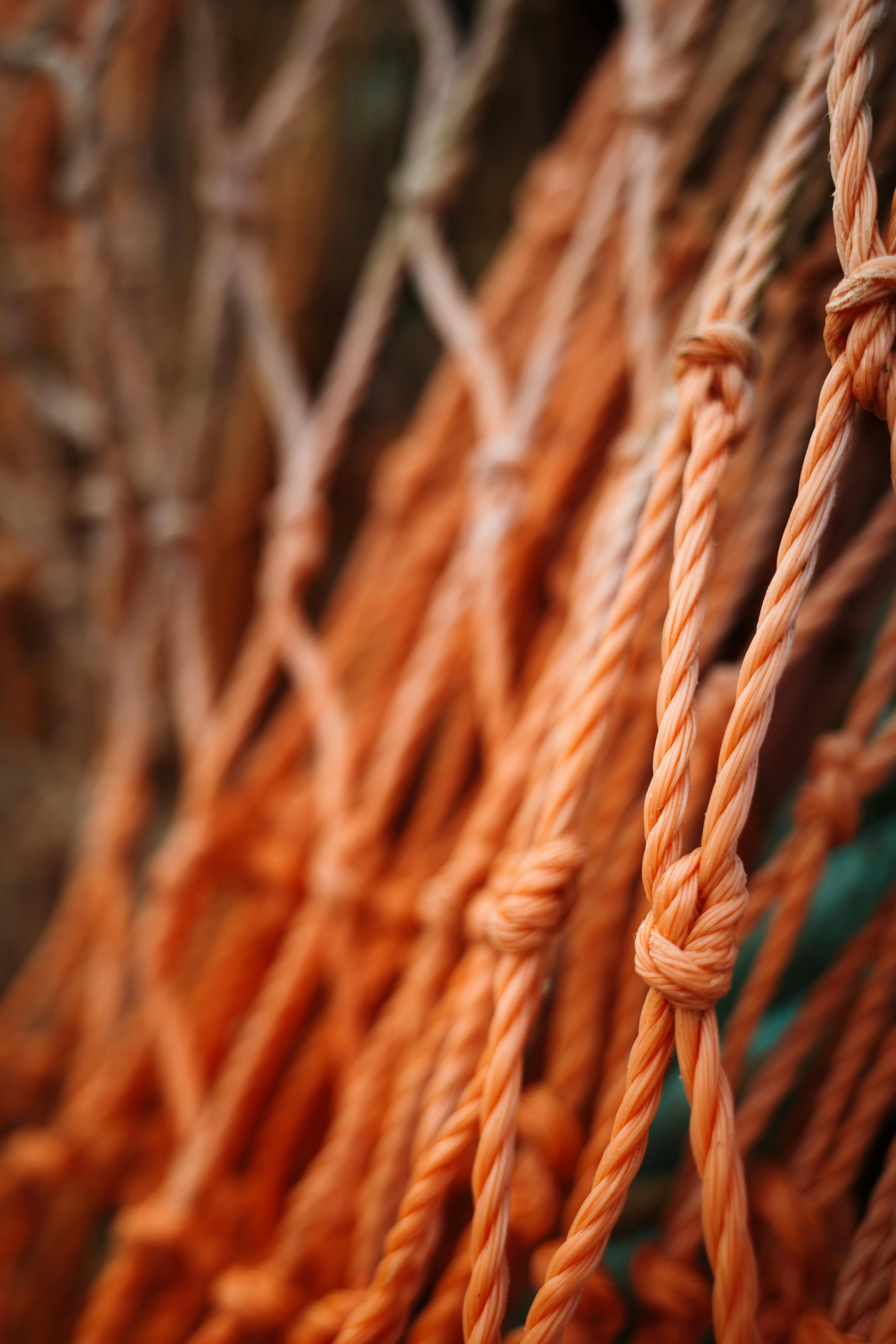 Detailed view of intertwined orange fishing nets showcasing intricate knots.