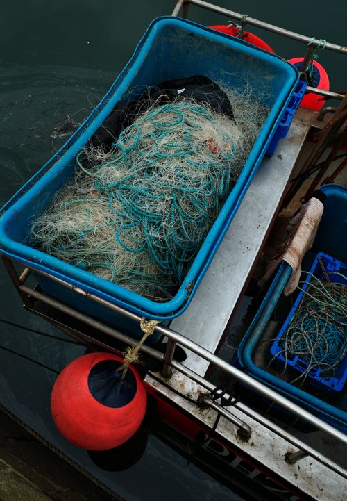 Free Close-up of tangled fishing nets in blue containers on a dock, featuring a buoy. Stock Photo