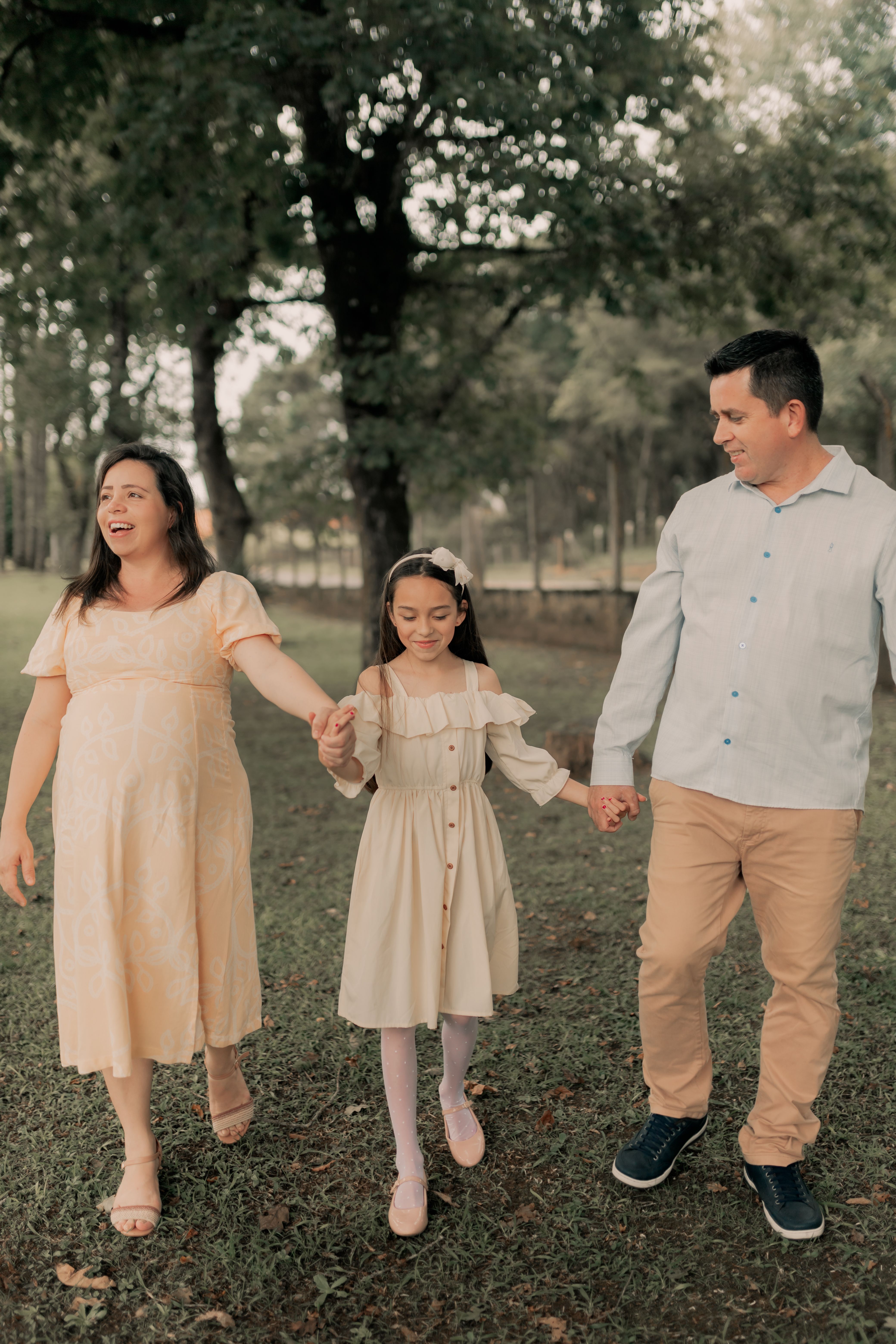 A family enjoying a walk in a sunny park holding hands, exuding happiness.