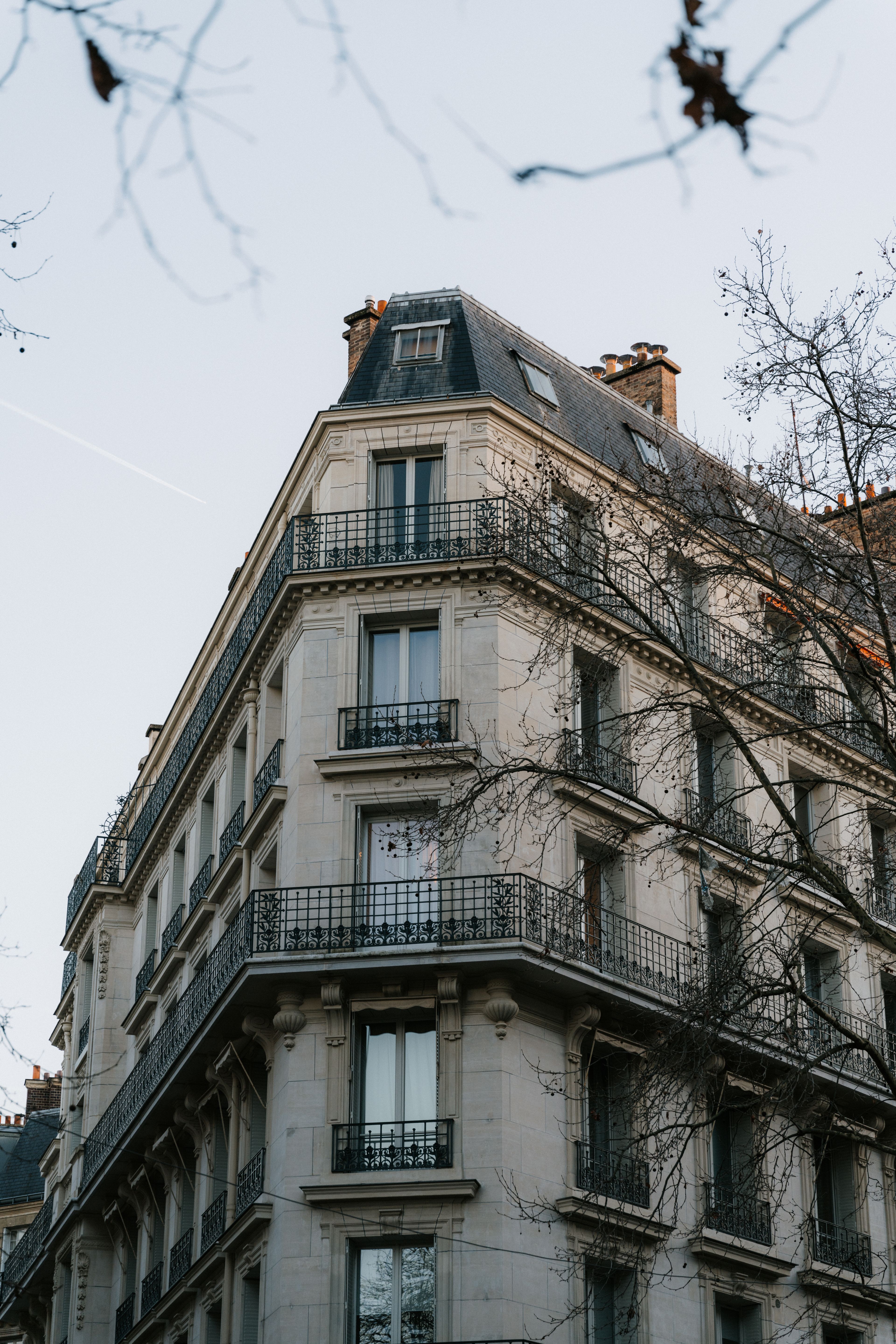 Immeuble d’habitation parisien aux balcons classiques, sous une lumière d’hiver douce.