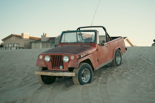 A classic red Jeep parked on a sandy beach, evoking a nostalgic vintage vibe.