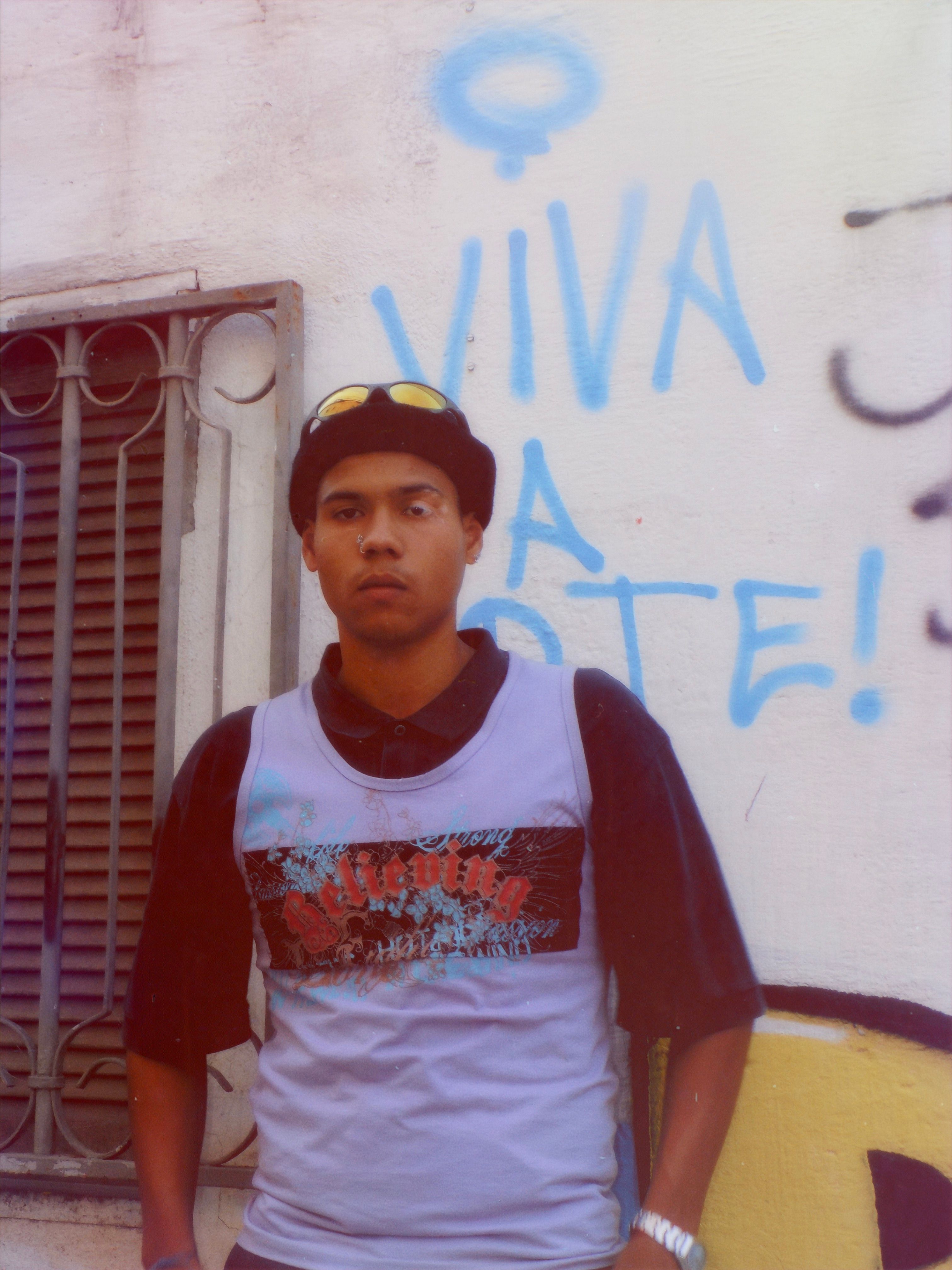 Young man in streetwear by graffiti wall in Minas Gerais, Brazil, showcasing urban fashion.