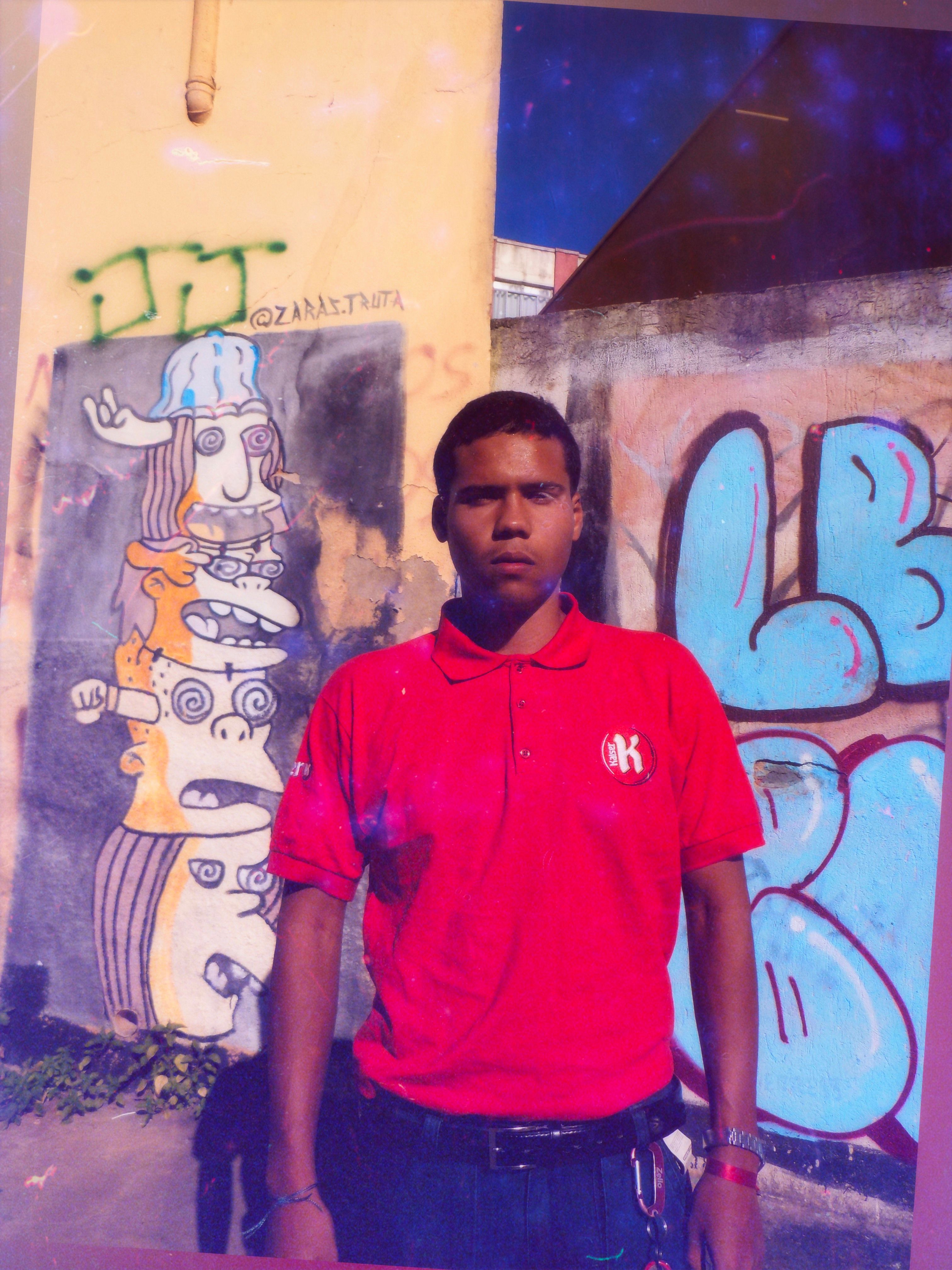 Young man in vibrant street fashion against colorful graffiti in Minas Gerais.