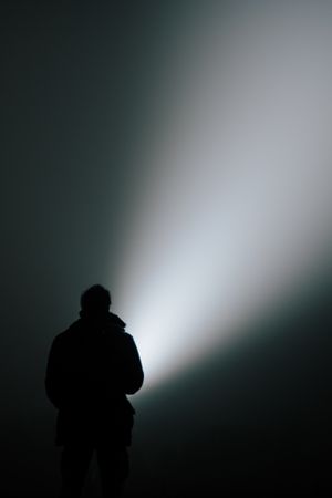 Silhouette with a flashlight beam in fog — photo by Jan Reichelt on Pexels