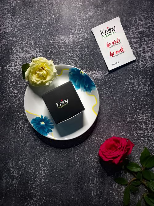 Free Sophisticated skincare flat lay featuring lip products and roses on a textured surface. Stock Photo