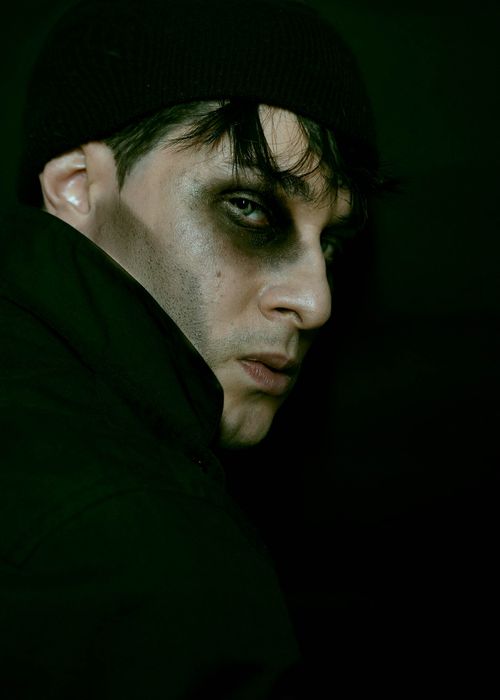 Free Close-up portrait of a pensive man with dark makeup in low light, evoking intrigue. Stock Photo