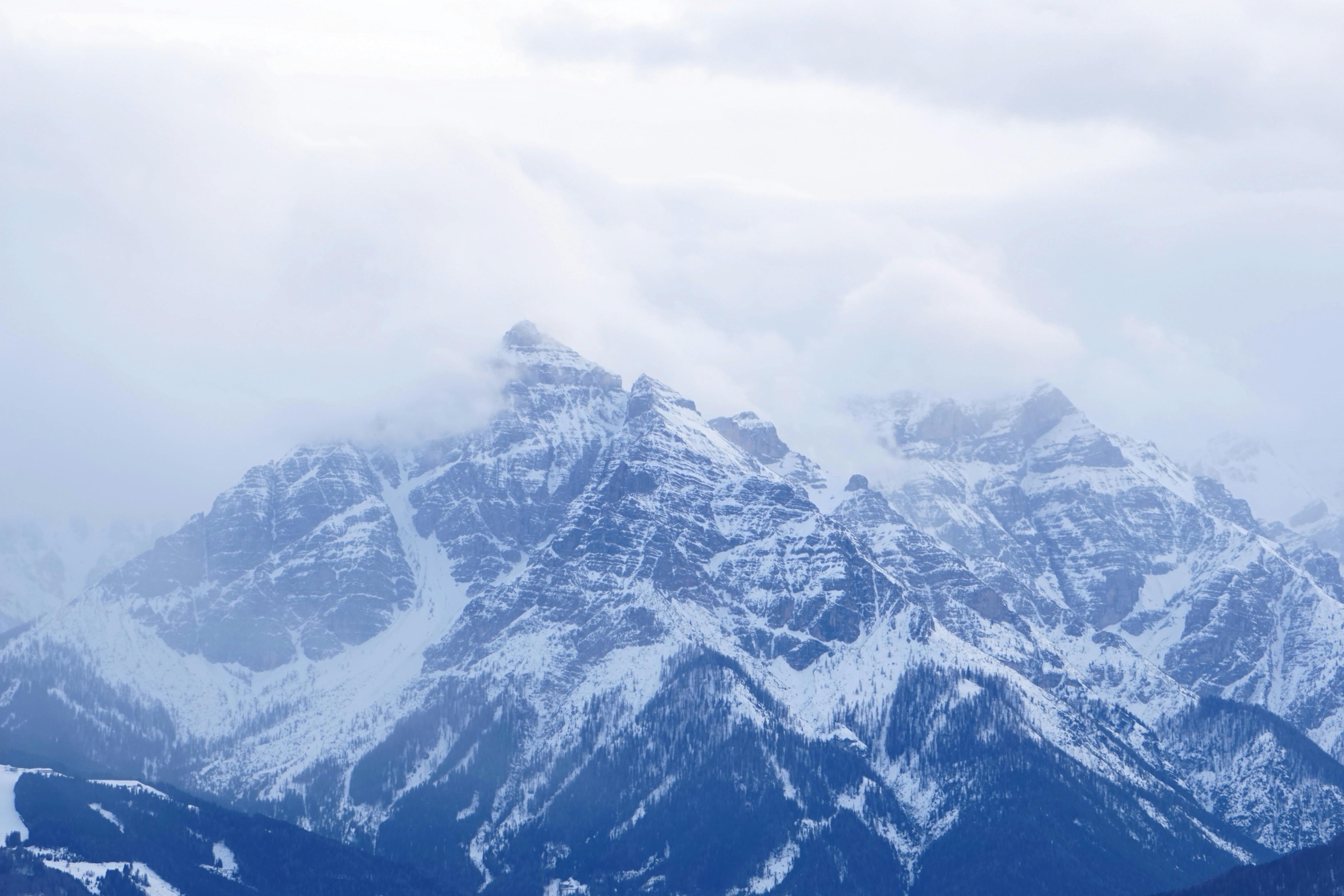 Scenic view of snow-covered mountain peaks surrounded by clouds.