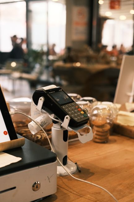 A digital payment terminal on a cozy café counter, suggesting a modern lifestyle. A digital payment terminal on a cozy café counter, suggesting a modern lifestyle.