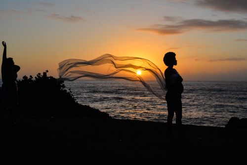 Free Silhouette of a pregnant woman by the sea at sunset with a flowing fabric. Stock Photo