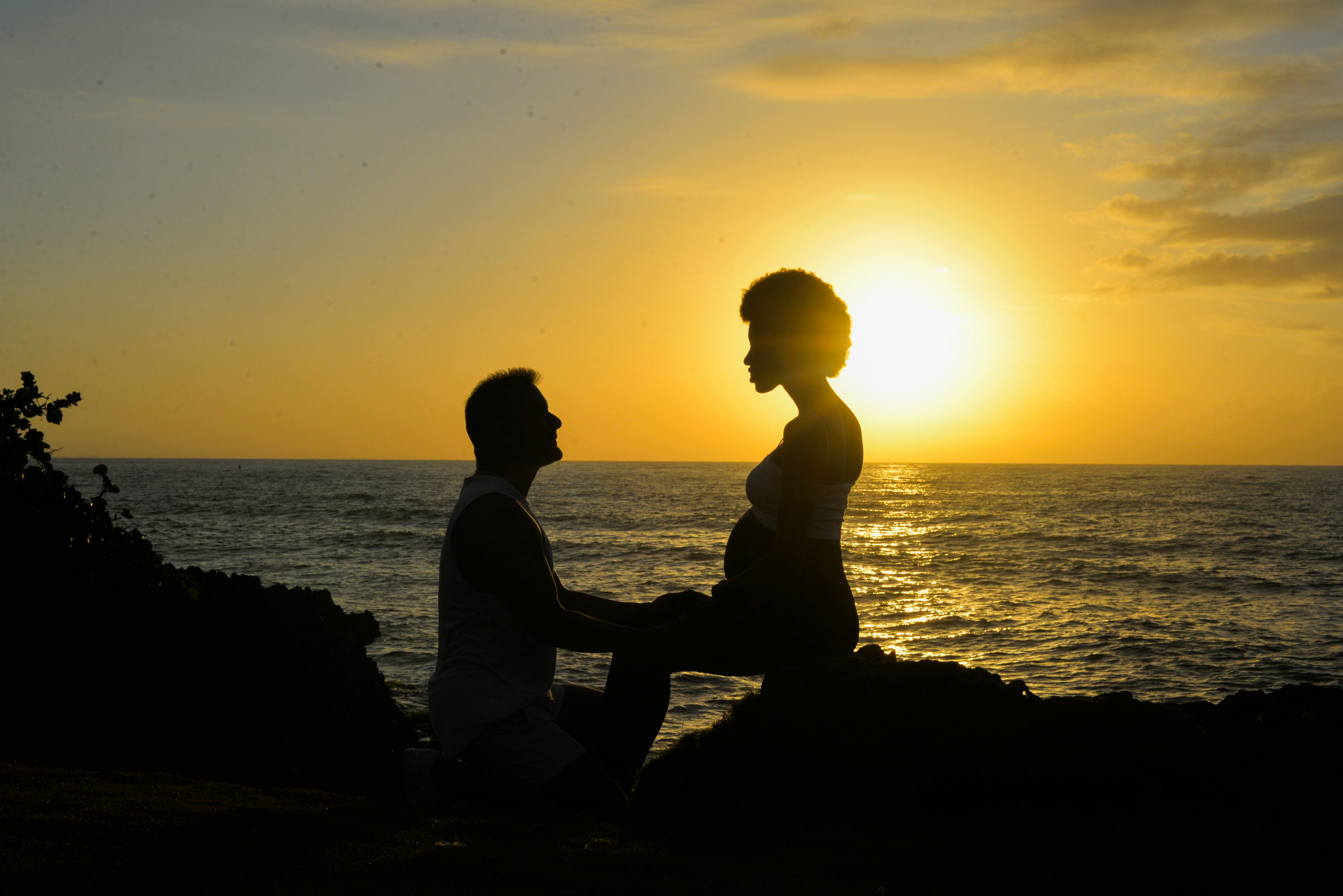 Romantic sunset moment with a pregnant couple by the ocean, capturing love and anticipation.