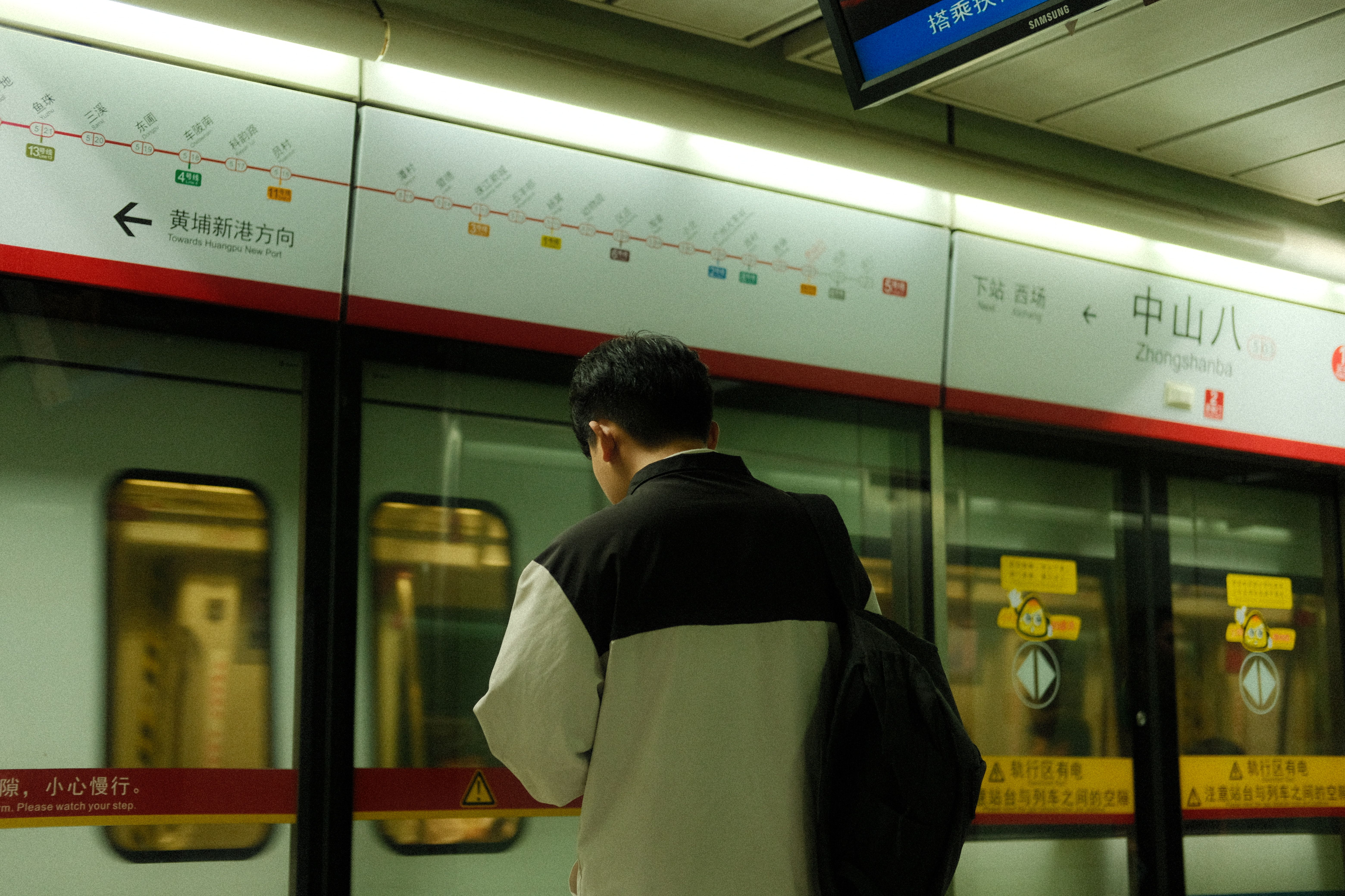A man standing at Zhongshanba subway station, looking away.