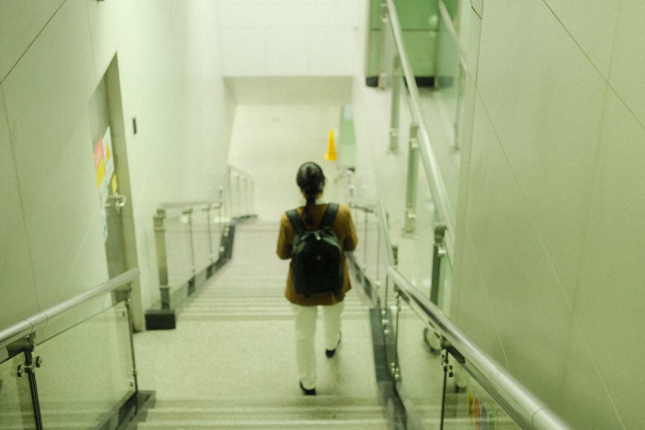 rear view of person descending indoor staircase with backpack modern s