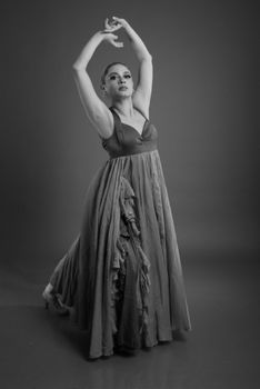 Black and white portrait of a graceful ballet dancer in a long dress performing a pose.