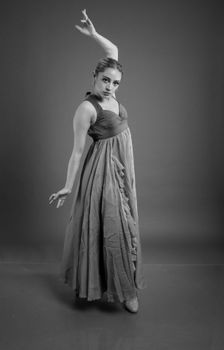 A graceful ballet dancer striking a pose in a flowing dress, captured in a studio setting.