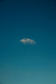 A single cloud floats in an expansive, clear blue sky, offering a minimalist aesthetic.