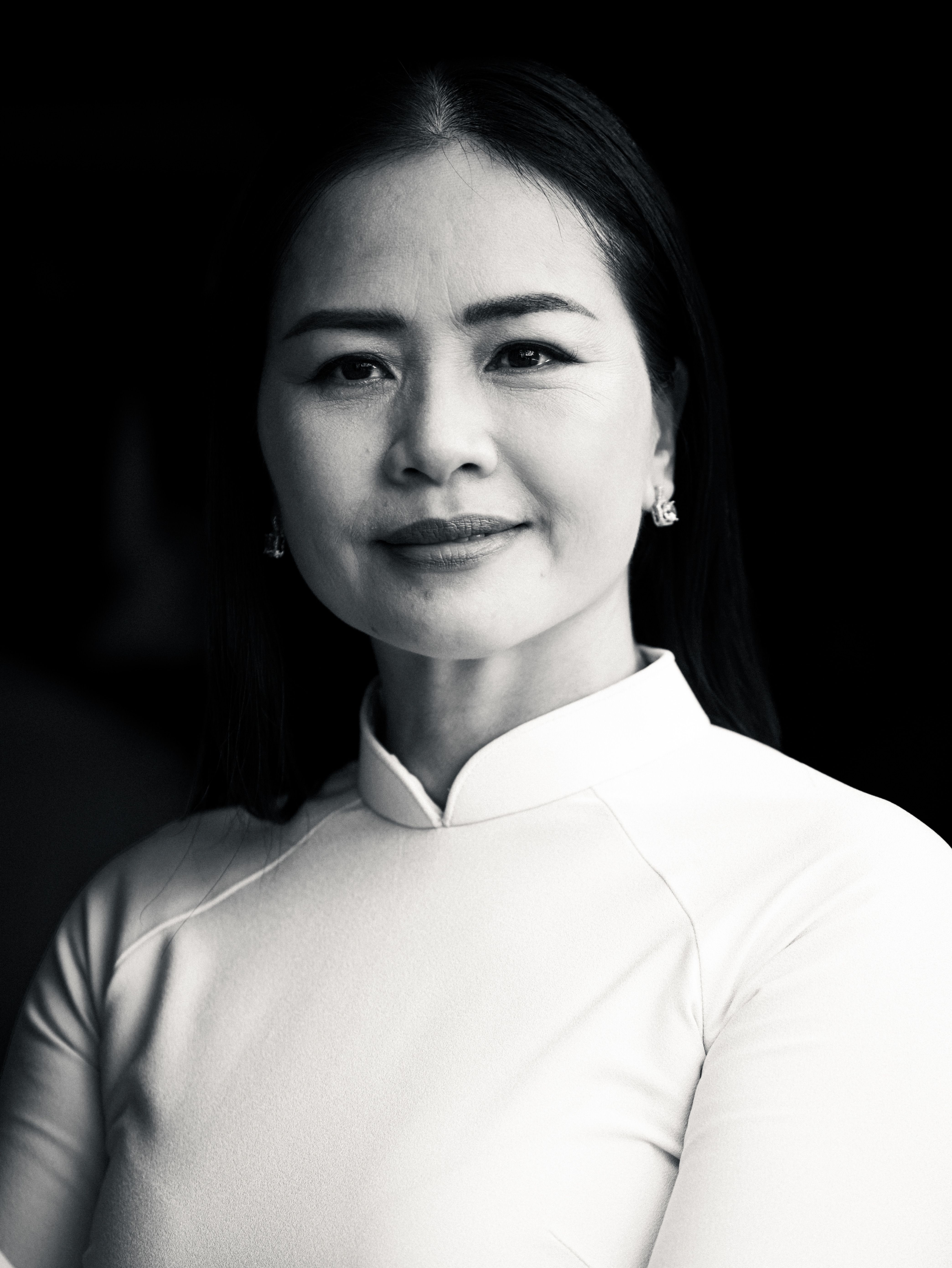 Black and white portrait of a confident Vietnamese woman wearing an Ao Dai, exuding elegance and grace.