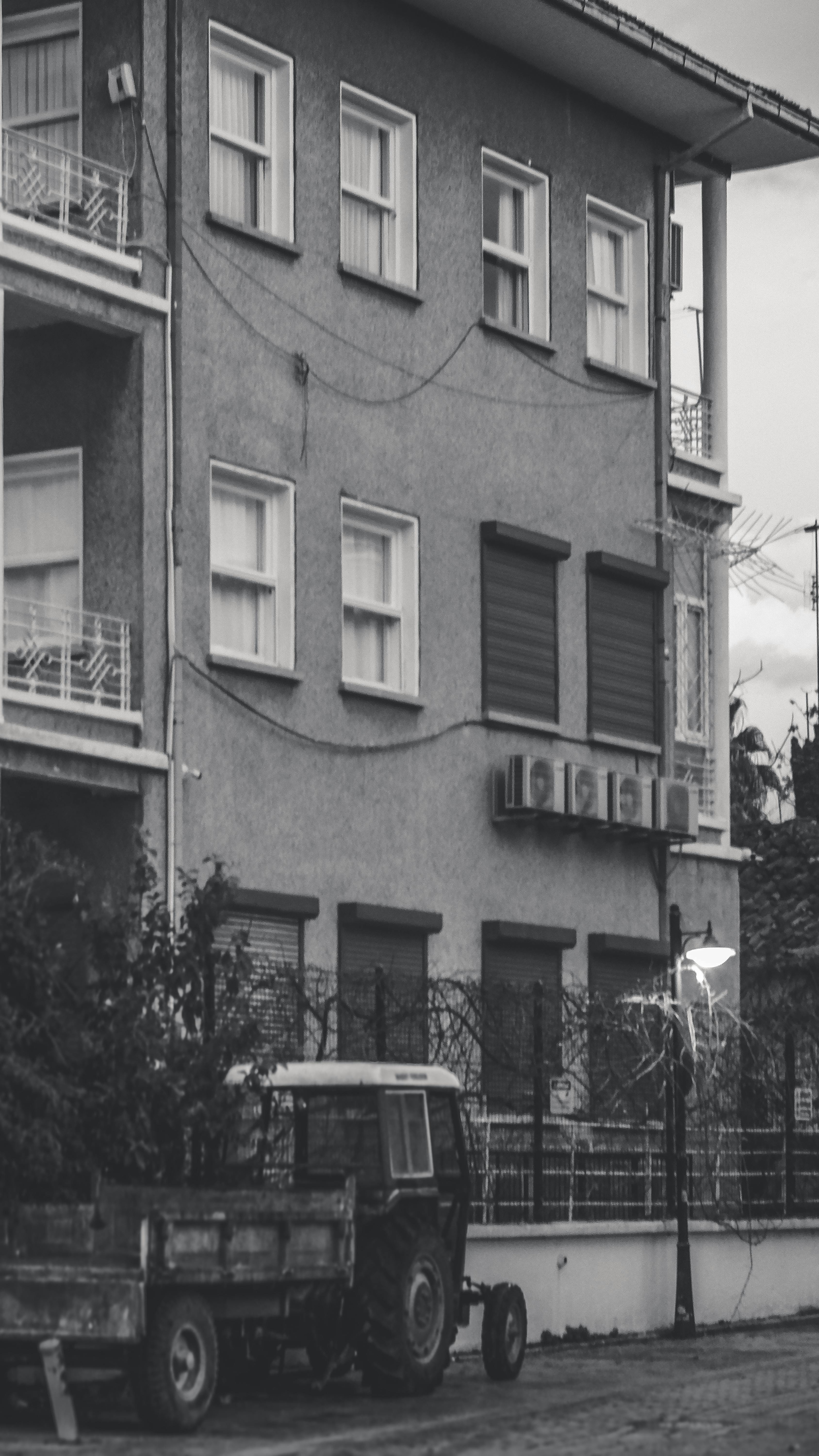 A vintage tractor parked beside an old apartment building showing urban decay and nostalgia.