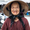 在越南会安，一位戴着圆锥形帽子的老妇人面带温暖的微笑