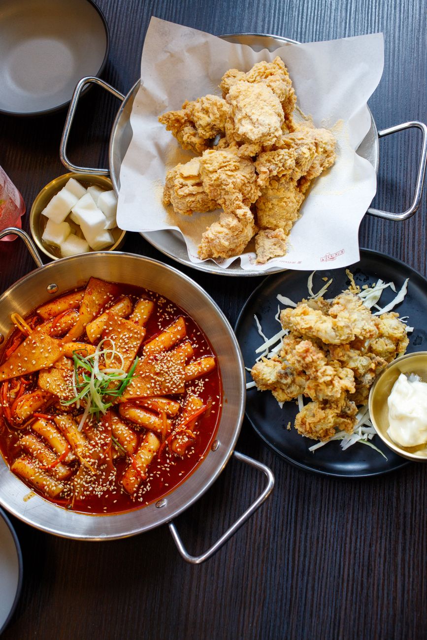 Nashville hot chicken, birria tacos with rich consommé for dipping, and Korean-style gochujang glazed wings arranged together
