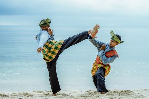 Free Two men in traditional attire practicing martial arts on a sandy beach. Stock Photo