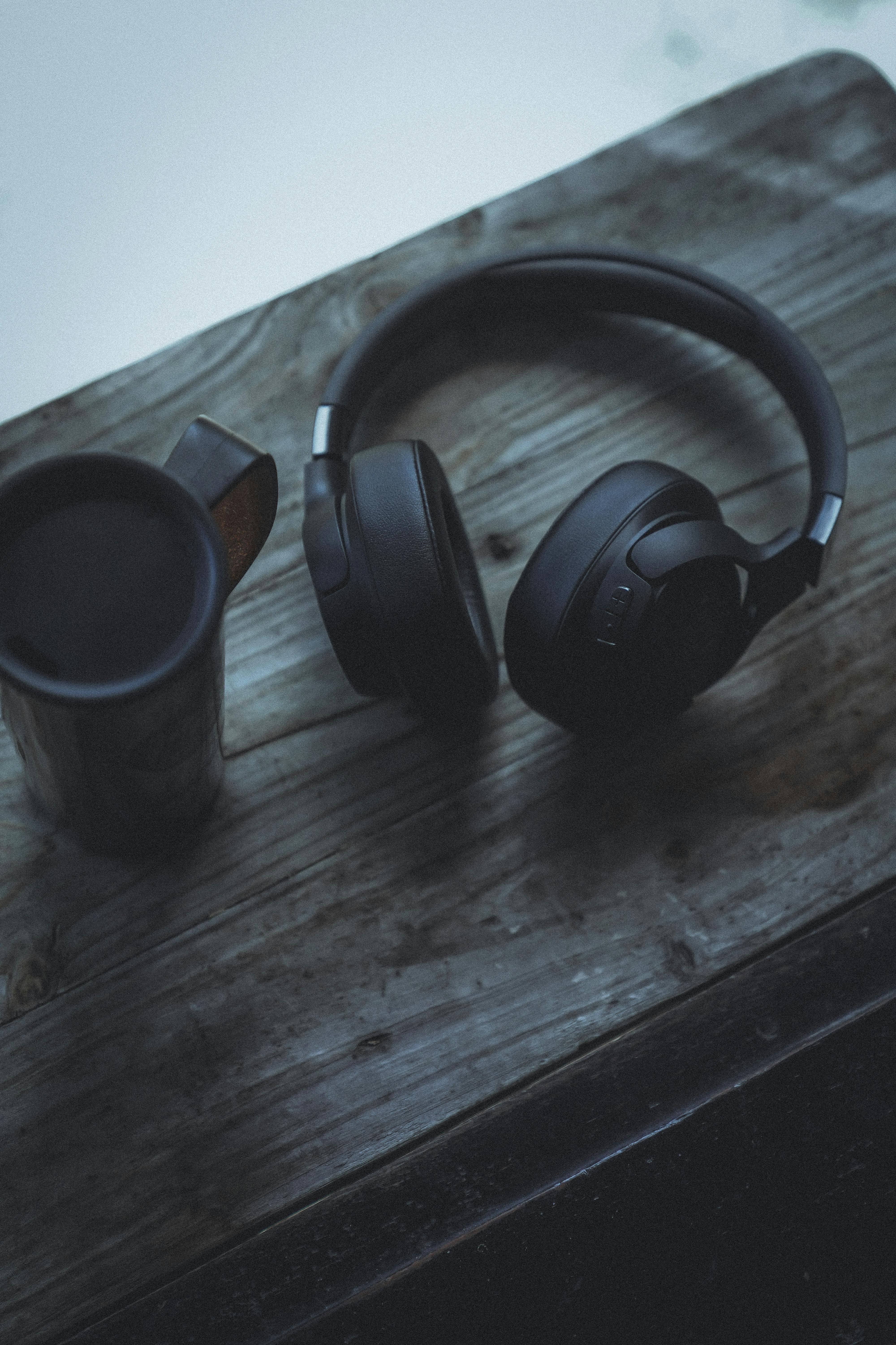 Miễn phí Tai nghe và tách cà phê thời trang trên chiếc bàn gỗ mộc mạc, hoàn hảo cho cảm giác làm việc tại nhà. Ảnh lưu trữ