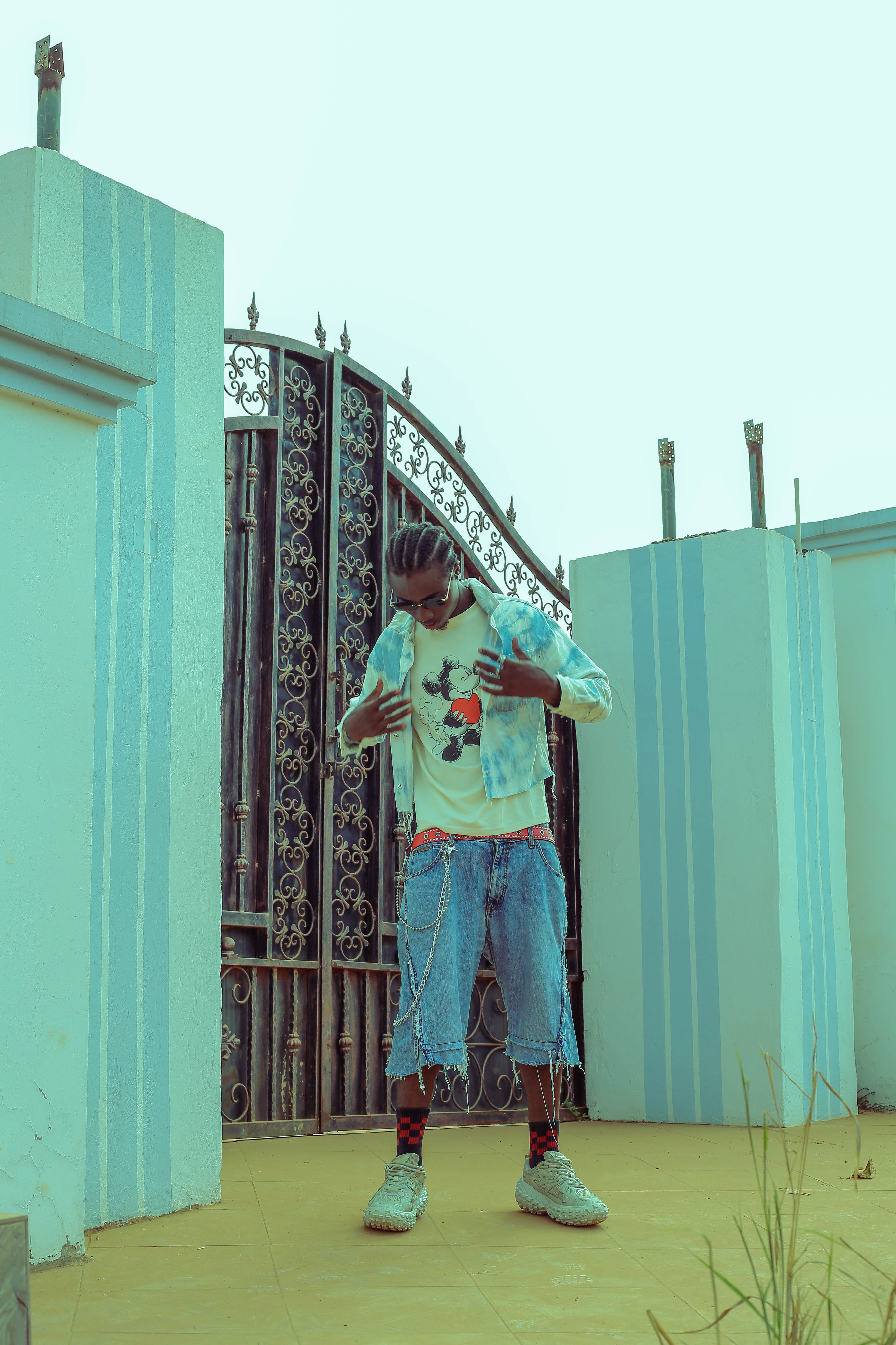 Stylish young man posing in casual attire in front of a decorative gate.