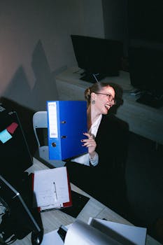 Joyful office scene of a woman sitting at her desk with a blue binder.