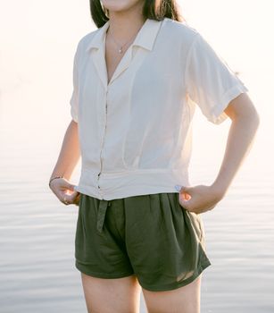 Woman standing by the water in casual attire during daylight. Perfect for lifestyle or fashion themes.