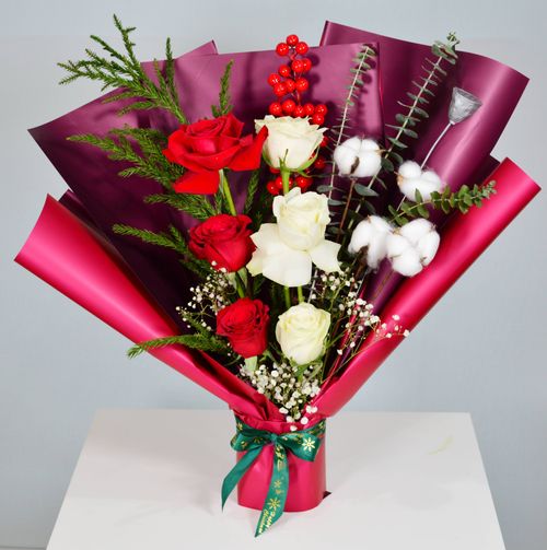 Free Stunning bouquet featuring red and white roses, greenery, and berries in vibrant wrapping. Stock Photo